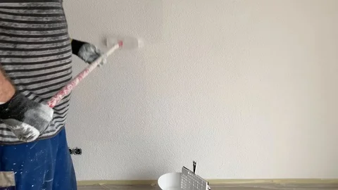 A man paints a wall in white Stock-Footage 104760802