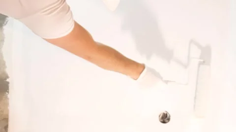 A man paints the wall white with a roller. Concept builder with a paint roller Stock Footage 250029941