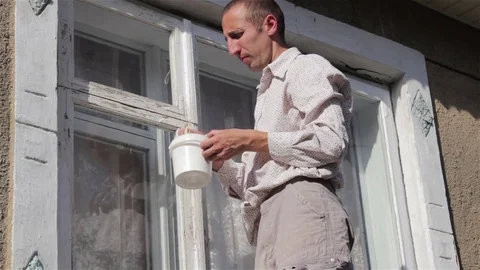 Man paints the white window Stock Footage 73114023