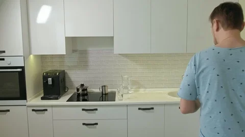 A man in pajamas drinking water in the kitchen. Morning Stock Footage 104036146