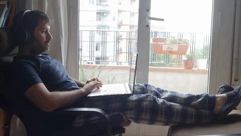Man in pajamas with laptop working on sofa at home Stock Footage