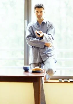 Man in pajamas using remote control Stock Photos