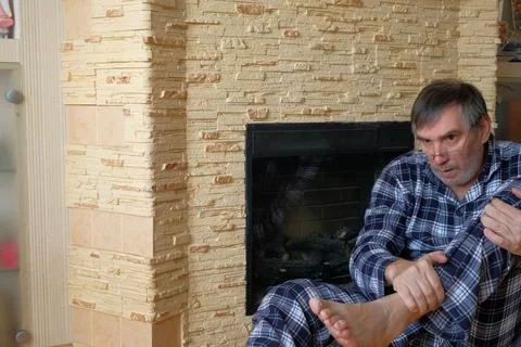 Man in Pajamas Using Smartphone by Fireplace at Home Stock Photos