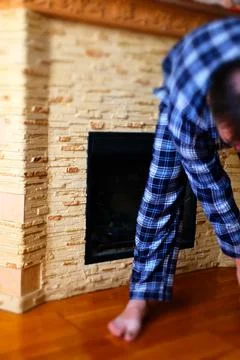 Man in Pajamas Using Smartphone by Fireplace at Home Stock Photos