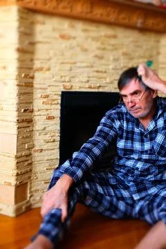 Man in Pajamas Using Smartphone by Fireplace at Home Stock Photos