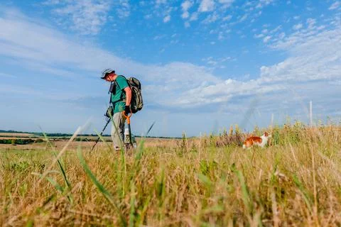 A man in a Panama hat and a backpack walks with a metal detector. Stock Photos