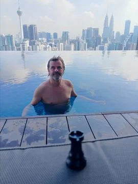 Man in a panoramic infinity pool overlooking the skyscrapers, kuala lumpur Stock Photos