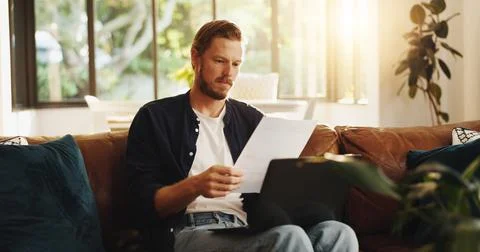 Man, paperwork and reading on sofa with laptop, writer and thinking for script Stock Photos