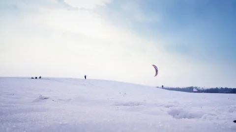 A man with parachute in his hand is walking away from camera on a snowy hill Stock Footage 88095427