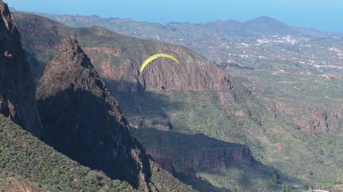 Man on paraglider approaches rock formation called Roque Grande on Gran Canaria Stock Footage 298121653