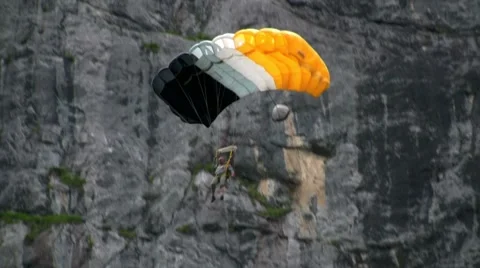 A man paraglides through a mountain pass near a waterfall. Stock Footage 8652133