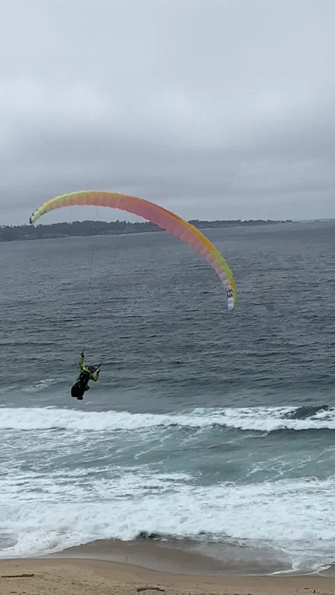 Man Paragliding back and forth at low altitude over the ocean in Monterey 動画素材 153329775