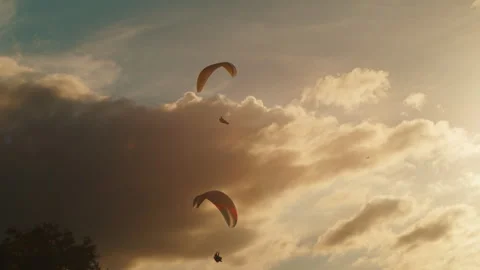Man paragliding under cloudy sky at sunset. Extreme Sport Concept Stock Footage 263857694