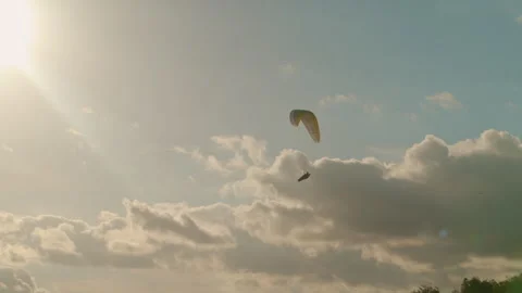 Man paragliding under cloudy sky at sunset. Extreme Sport Concept Stock Footage 263857744