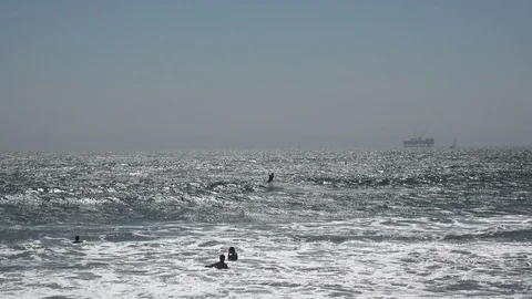 A man parasailing jumping a wave in the Pacific Ocean at Huntington Beach Stock Footage 113383996