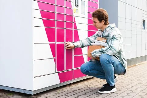 Man at a parcel locker for parcel pickup. This self-service terminal enable.. Stock Photos
