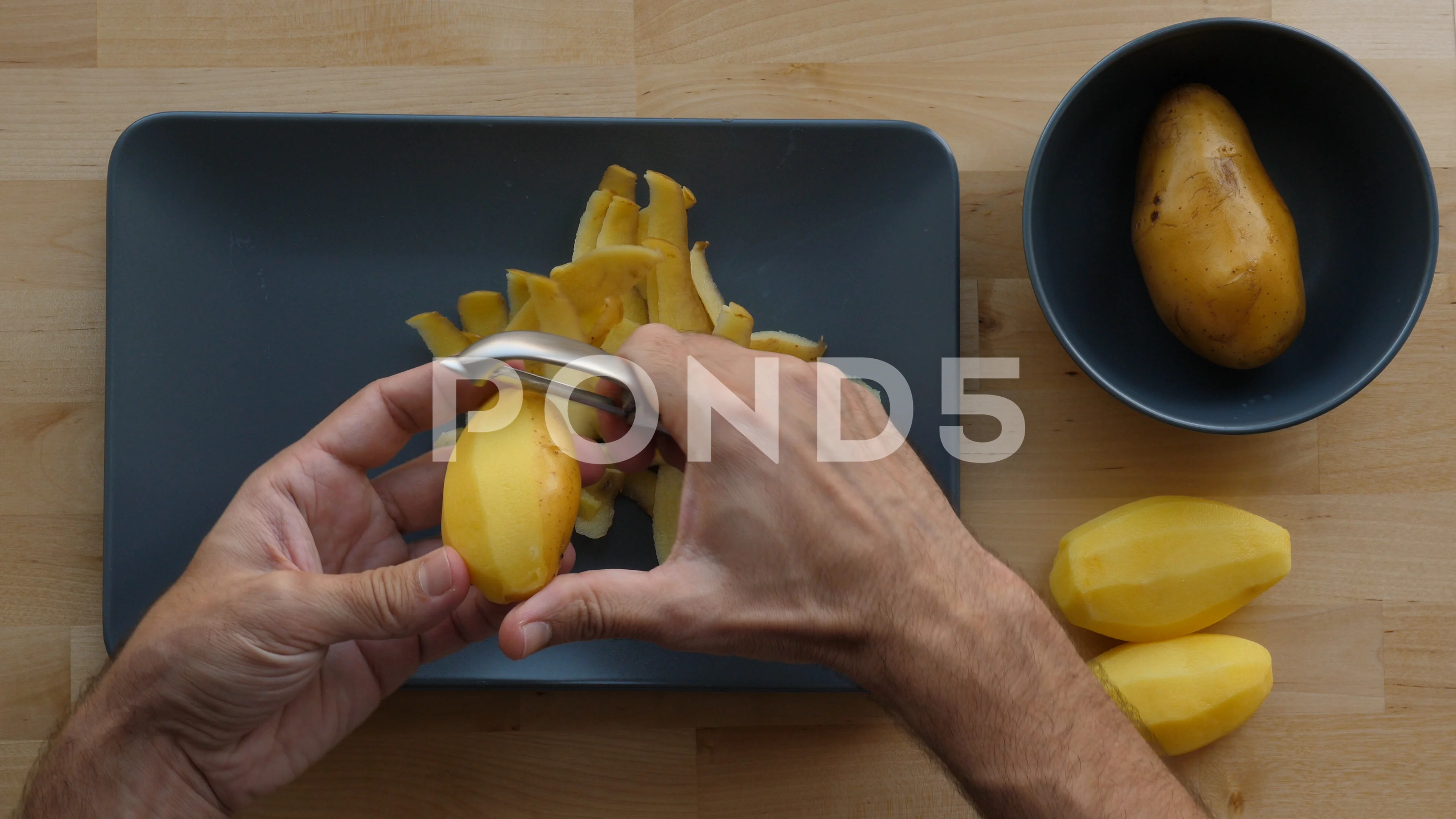 Boy using peeler to peel raw potato available as Framed Prints