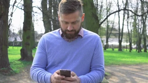 Man in park, browsing smartphone, portrait steadicam shot Vídeo Stock 74228234