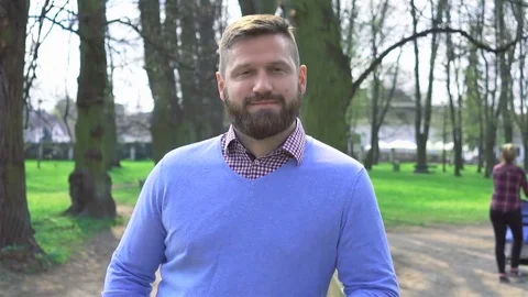 Man in park, smiling at camera, close portrait steadycam shot 库存影片 74236523