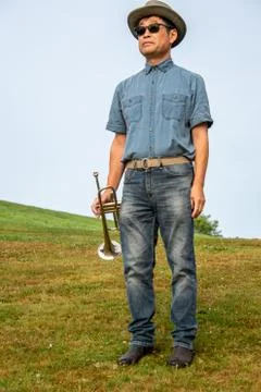 A man at a park taking a rest from playing the trumpet. Stock Photos