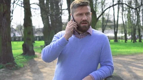 Man in park, talking by smartphone, portrait, steadycam shot 動画素材 74228178