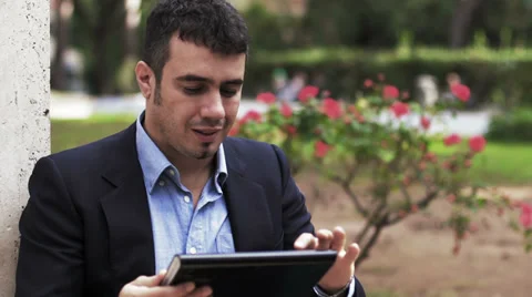 Man at a park using a computer tablet computer Stockbeeldmateriaal 32942570