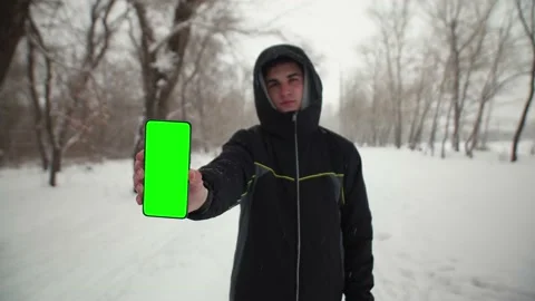 Man in park winter shows screen of phone of chomakey. Man holds a phone with a Stock Footage 149763126