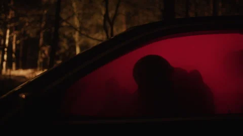 A man in a parked car with red light in it looking out the window 스톡 동영상 259065487