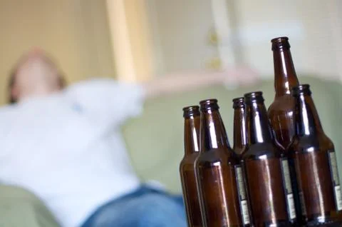 Man passed out on couch with empty beer bottles, angled Stock Photos