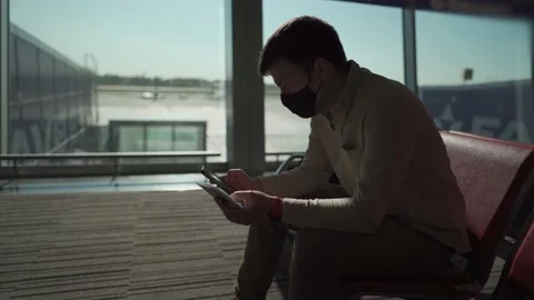 Man passenger with backpack in protective mask waiting for boarding a plane Stockbeeldmateriaal 154751687