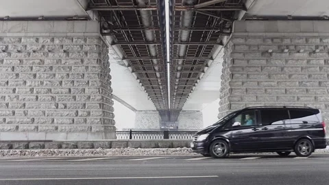 Man passes in black car by road under bridge at Stock Footage 299678692