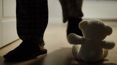 Man Passes By A Small Plush Bear Toy Sitting Alone On The Floor Video stock 124623581