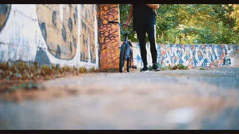 Man is passing by graffiti background with BMX. Copy space. 4K. Stock Footage 128308563