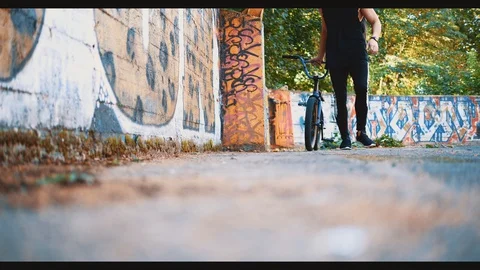 Man is passing by graffiti background with BMX. Copy space. 4K. Stock Footage 128308613