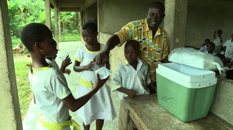 MAN PASSING OUT SACHETS OF WATER TO STUDENTS Stock Footage 57983259