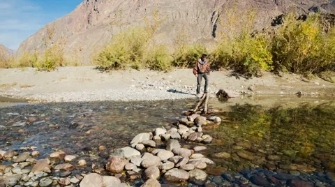 Man passing through the mountain river Stock Footage 48893537