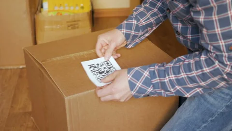 A man pastes a  QR code on a box. Delivery service. Online shop. Bar code. Stock Footage 118699489
