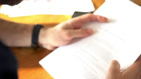 Man pausing to check smartwatch while reading document Stock Footage 63298151