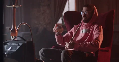 Man pausing videogame and refreshing with drink in hookah bar Stock Footage 229484931