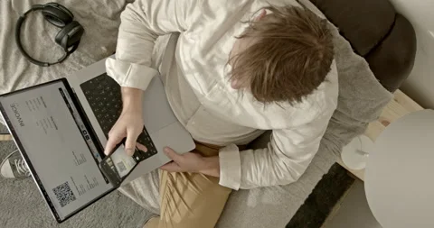 Man pays invoice with qr code via internet banking. He is sitting on the couch a 스톡 동영상 201166155