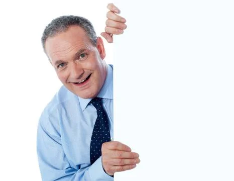 Man peeking behind empty white billboard Stock Photos