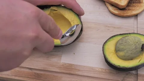 A man peeling an avocado using a knife on a cooking board Stock Footage 220368236