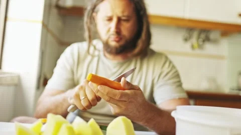 Man peeling carrot in kitchen Stock Footage 307995066