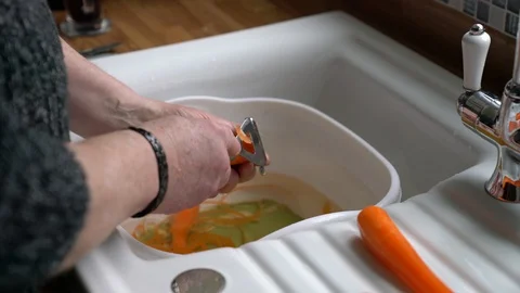 Man peeling carrots over kitchen sink for chopping, food preparation, 4k 스톡 동영상 86980189