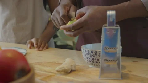 Man Peeling Ginger Root while Cooking with Kid Stock Footage 305701159