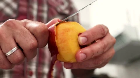 Man peeling a peach with a knife seen up close in 4K Stock Footage 219722406