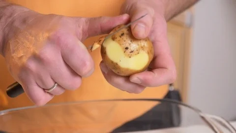 Man peeling potatoes using dull knife Stock Footage 121285733
