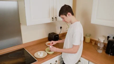 Man peeling shell off boiled egg over bowl. Male removing egg shell while Stock Footage 303064155