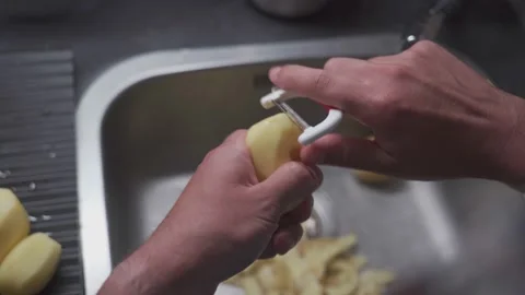 A man peels potatoes with a special vegetable peeler. Healthy food theme, male Stock Footage 207194963