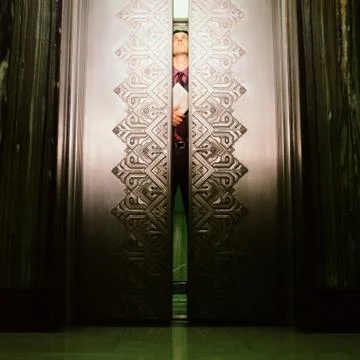 Man peering through elevator doors Stock Photos